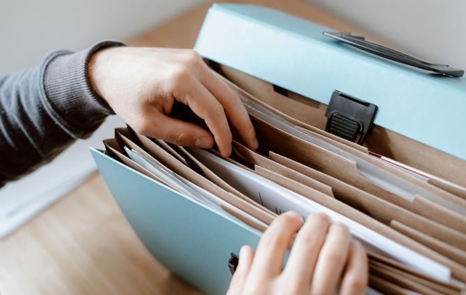 Close up of a student's hands flipping through a file folder containing documents